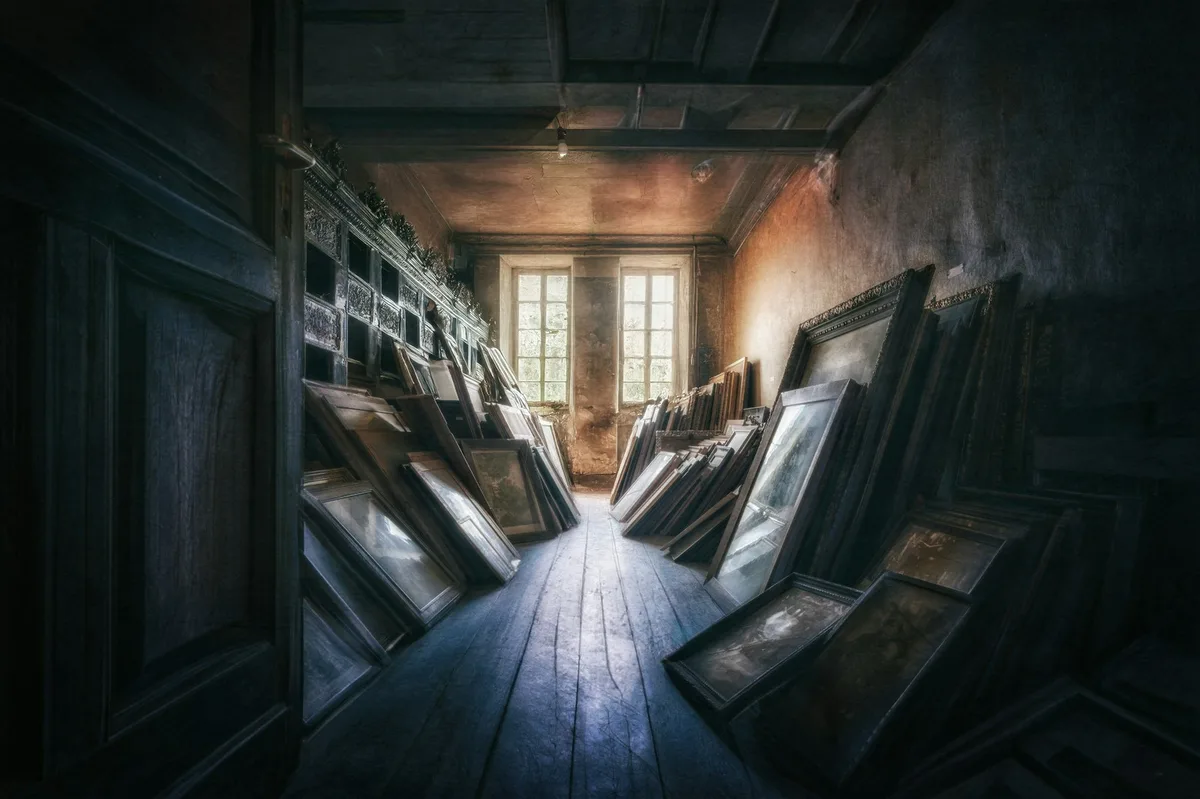Dusty storeroom stacked with framed pictures leaning against the walls