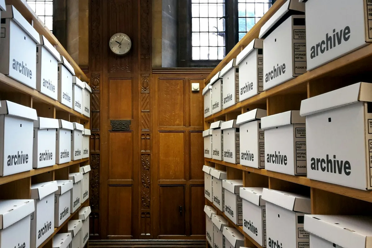 Rows of white archive boxes filling wooden storage shelves